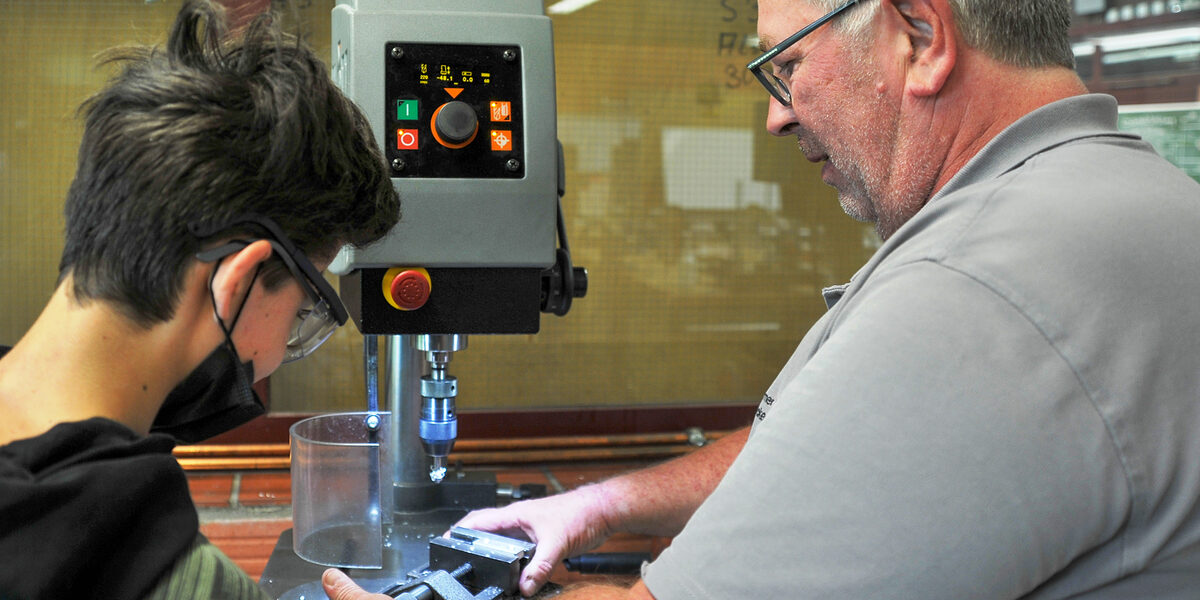 Präzision gefragt: An der Senkmaschine in der Metallwerkstatt zeigt Ausbildungsmeister Michael Becker, wie man Material durch Zerspanung in die richtige Form bringt.