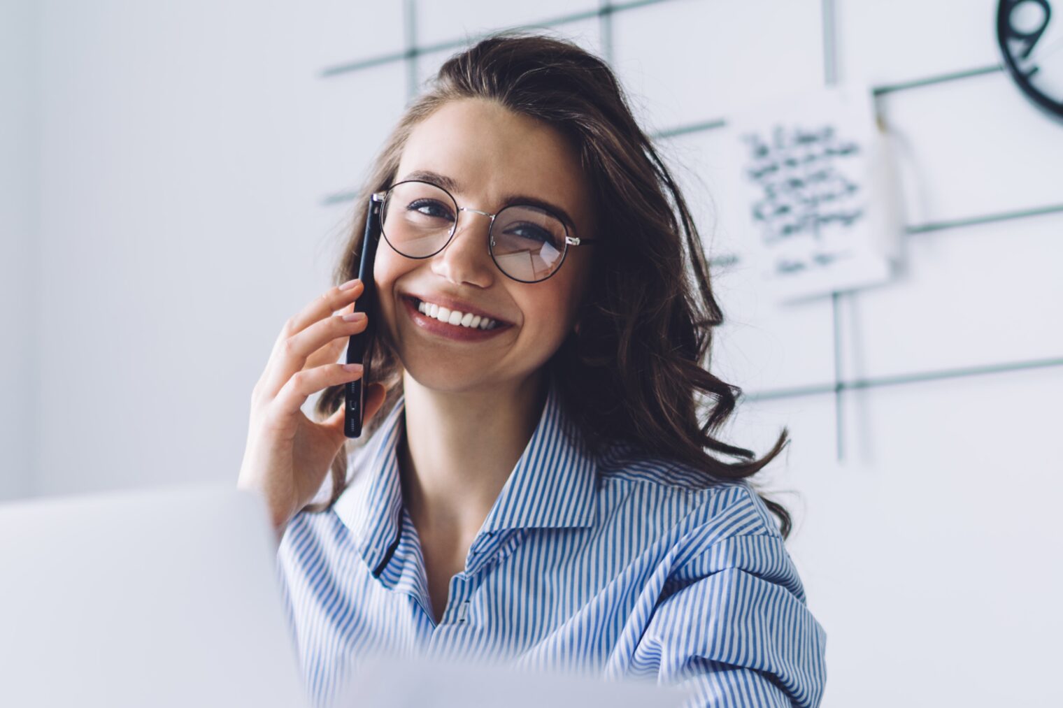 Junge Frau lächelt in die Kamera und telefoniert mit dem Handy Stellenausschreibung: QualiTec GmbH sucht Sachbearbeiter Entgeltabrechnung (w/m/d). 